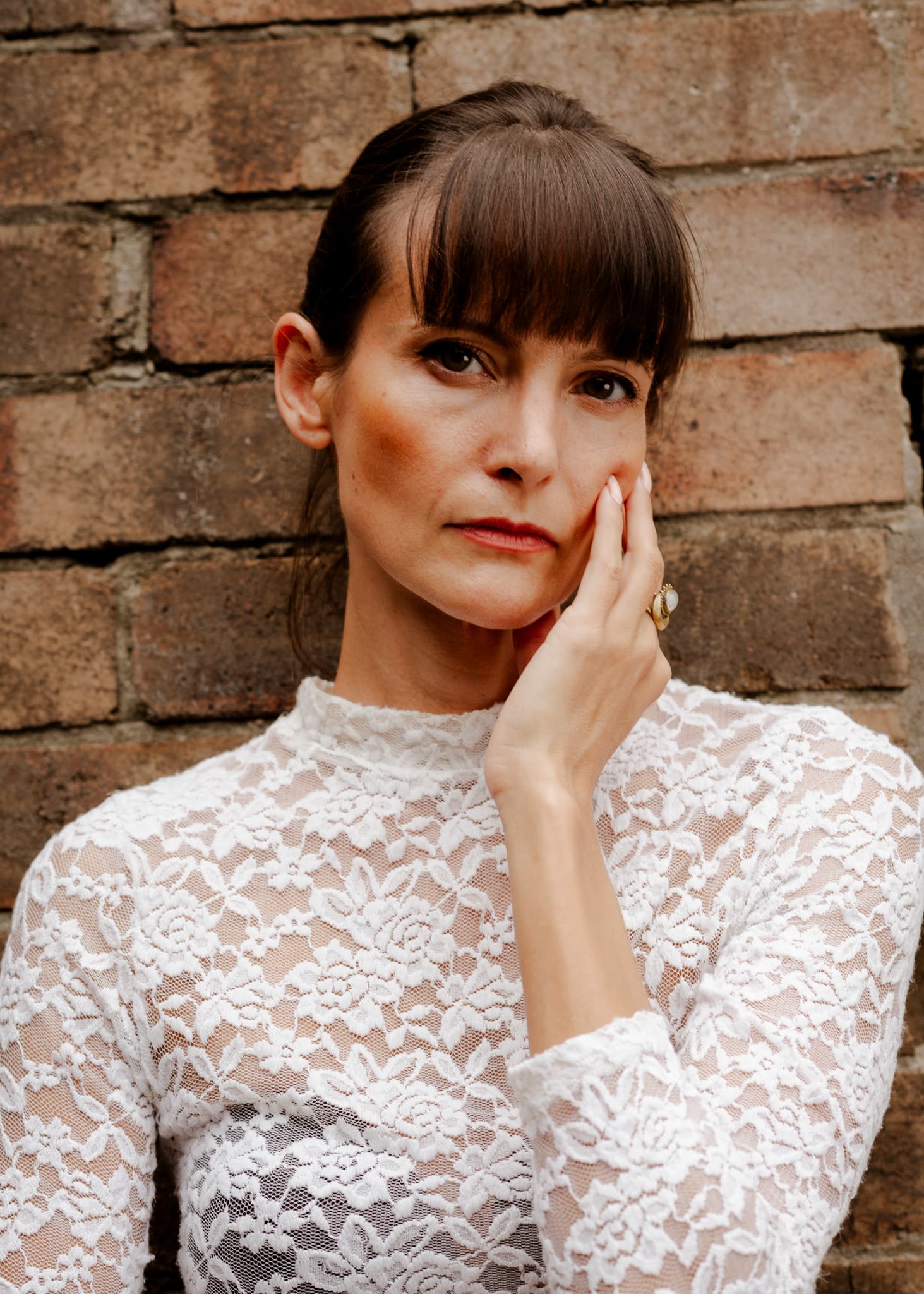 Portrait of a woman in white lace against brick
