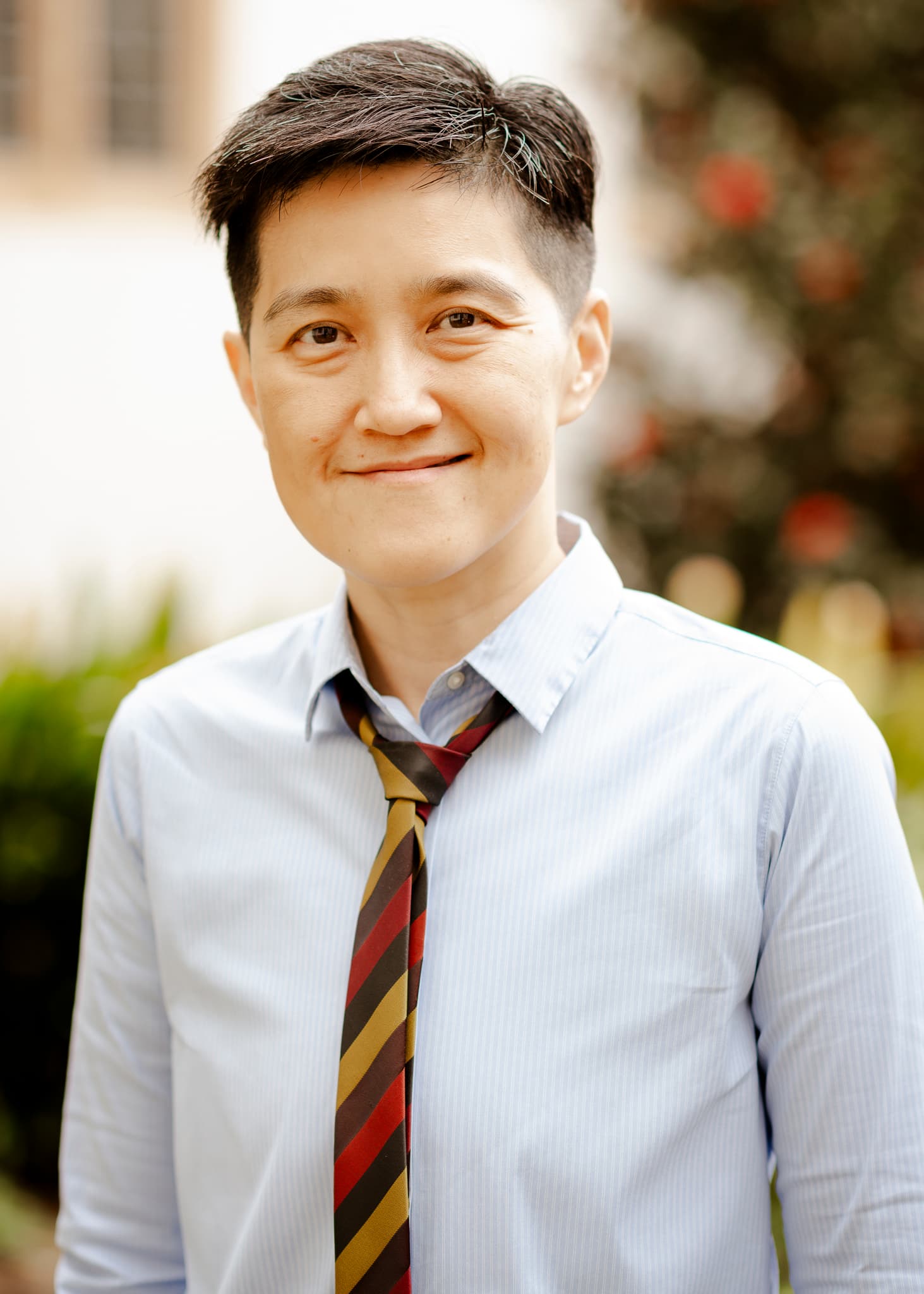 Portrait of a smiling person in a blue striped shirt and tie
